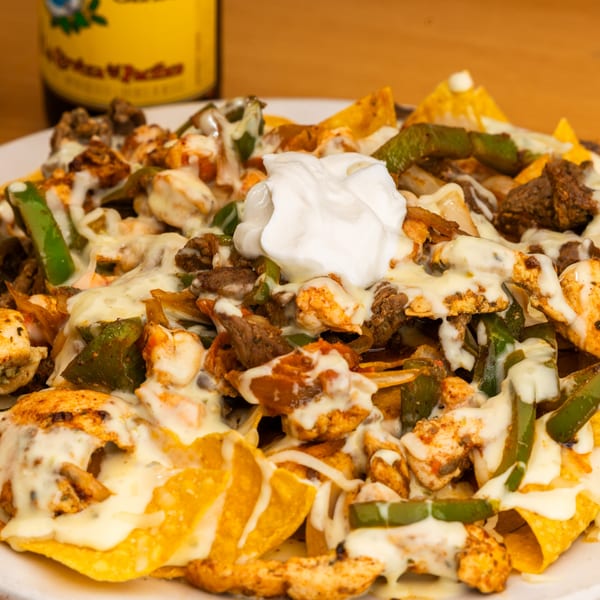 Sr. Tequila's nachos with steak, chicken, peppers, onions, melted cheese, and a dollop of sour cream.