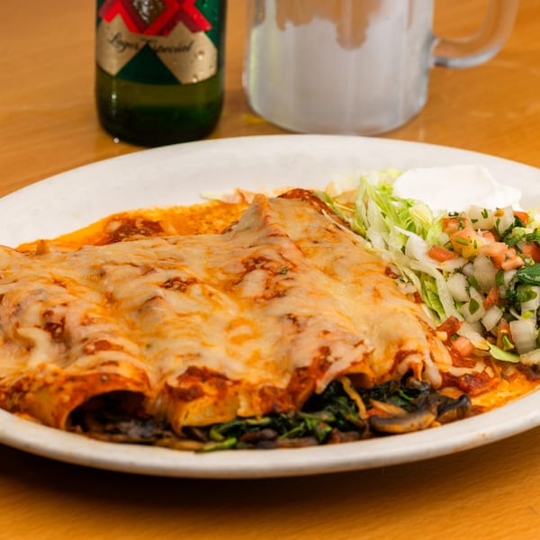 Three cheesy enchiladas with red sauce, a side of lettuce, pico de gallo, and sour cream.