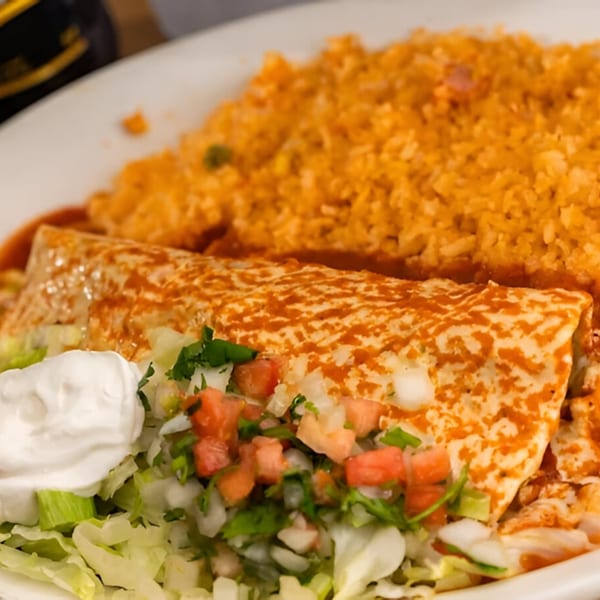 A Sr. Tequila Mexican Grill burrito with red sauce, rice, lettuce, pico de gallo, and sour cream.