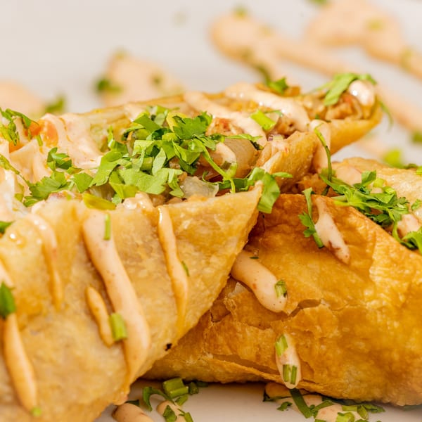 Crispy golden-brown Mexican flautas topped with creamy sauce, fresh cilantro, and green onions.