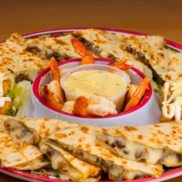 A platter of cheesy quesadilla slices surrounds a bowl of creamy dip and shrimp at Sr. Tequila Mexican Grill.