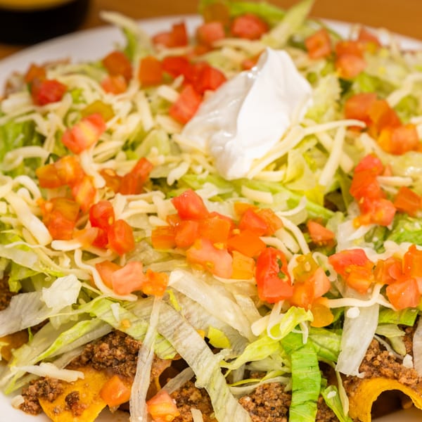 Sr. Tequila's nachos with ground beef, shredded lettuce, diced tomatoes, cheese, and sour cream.